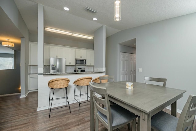 dining area featuring vaulted ceiling, dark hardwood / wood-style flooring, and a textured ceiling