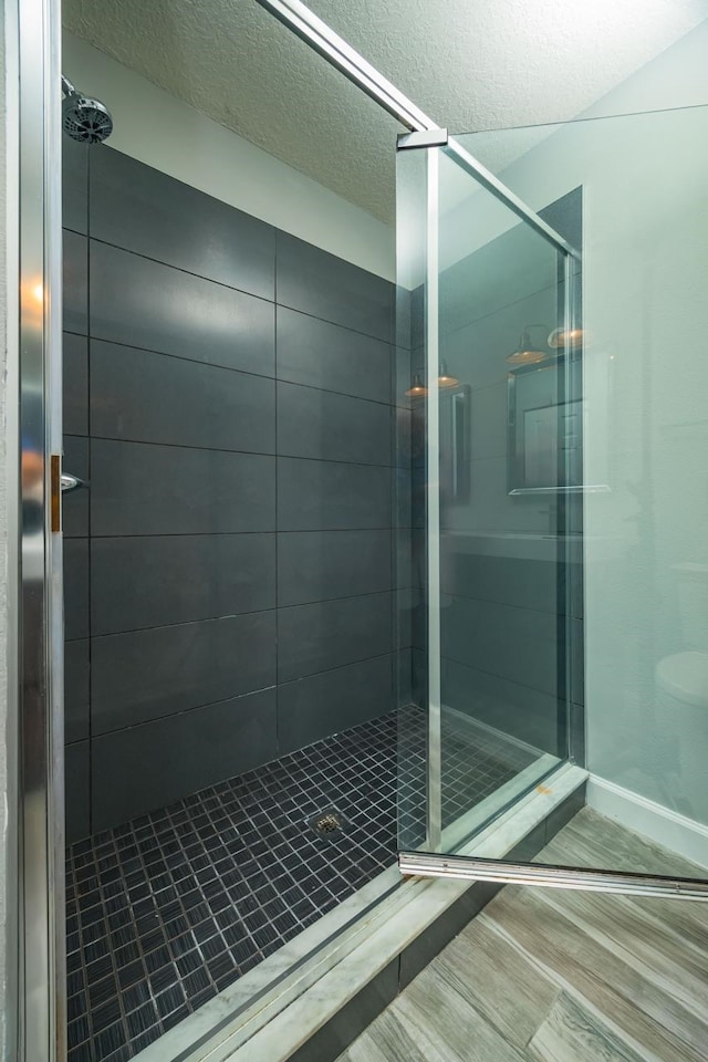 bathroom with tiled shower and a textured ceiling