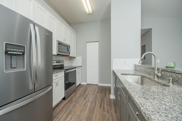 kitchen featuring light stone counters, sink, white cabinets, and stainless steel appliances