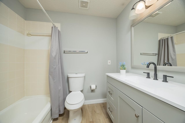 full bathroom with vanity, toilet, wood-type flooring, and a textured ceiling