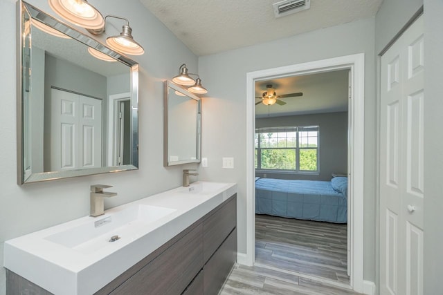 bathroom featuring a textured ceiling, vanity, hardwood / wood-style flooring, and ceiling fan