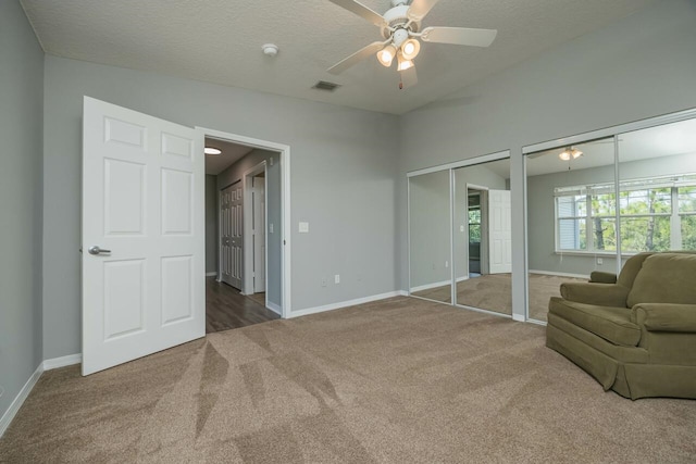 bedroom featuring ceiling fan, carpet floors, a textured ceiling, and multiple closets