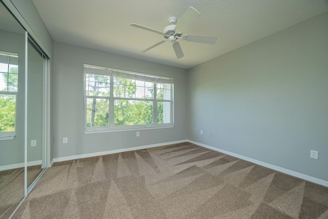 empty room with carpet flooring, ceiling fan, and plenty of natural light