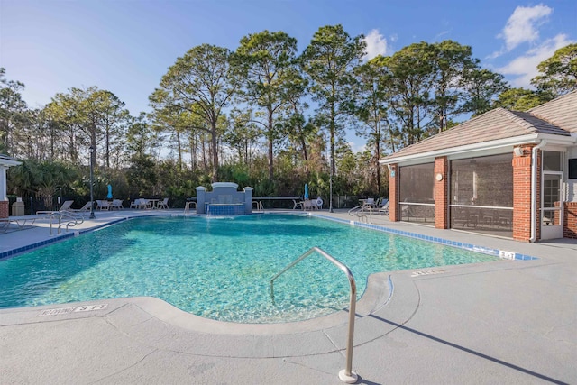 view of pool featuring pool water feature, a sunroom, and a patio