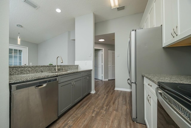 kitchen featuring a textured ceiling, stainless steel appliances, white cabinetry, and dark hardwood / wood-style floors