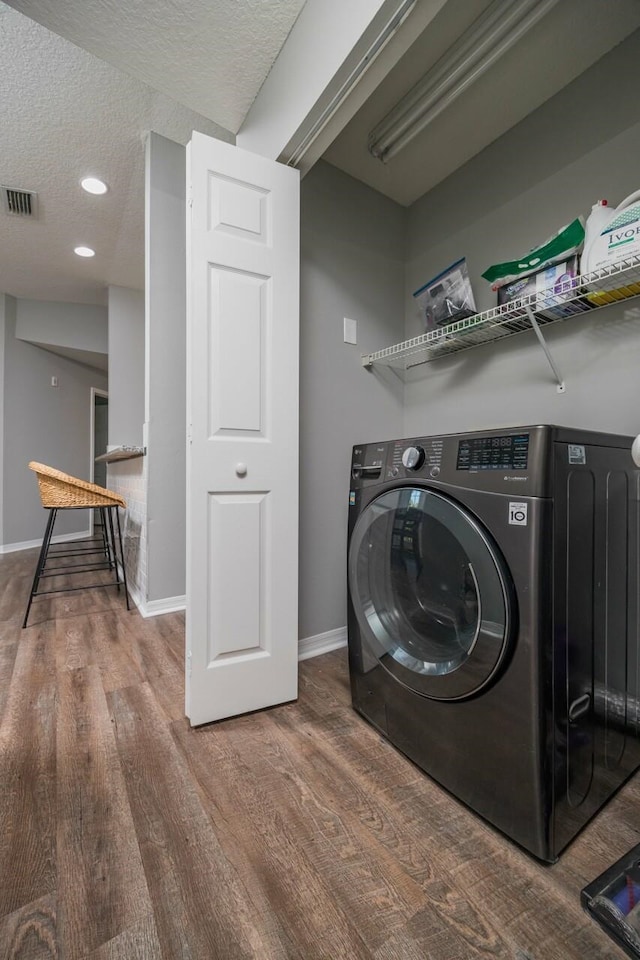 laundry room featuring wood-type flooring, a textured ceiling, and washer / dryer