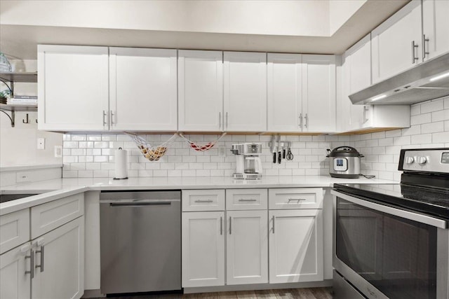 kitchen featuring white cabinets, decorative backsplash, appliances with stainless steel finishes, light countertops, and under cabinet range hood