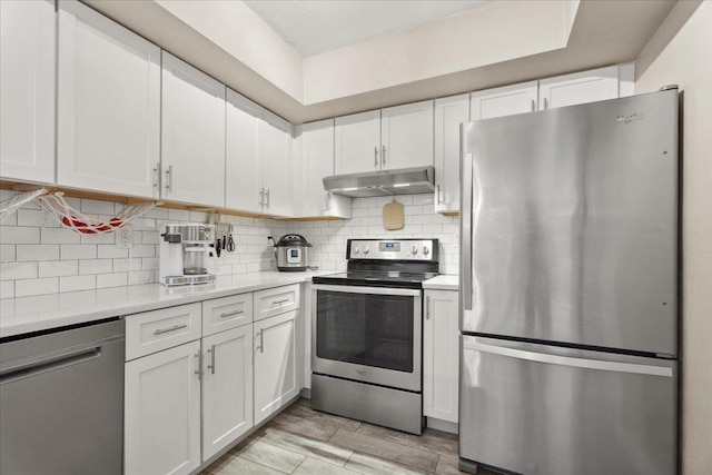 kitchen featuring white cabinets, decorative backsplash, appliances with stainless steel finishes, light countertops, and under cabinet range hood