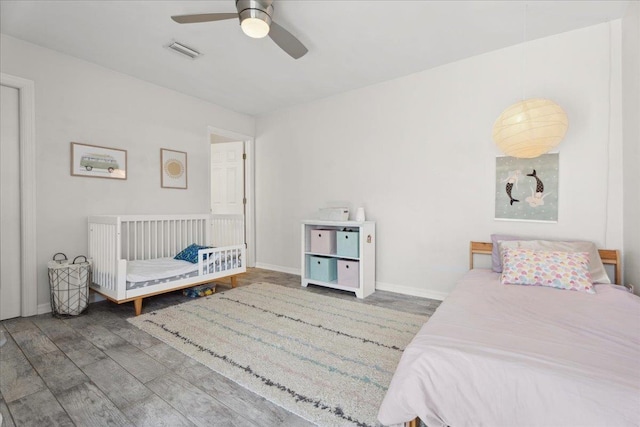 bedroom featuring a ceiling fan, baseboards, visible vents, and wood finished floors