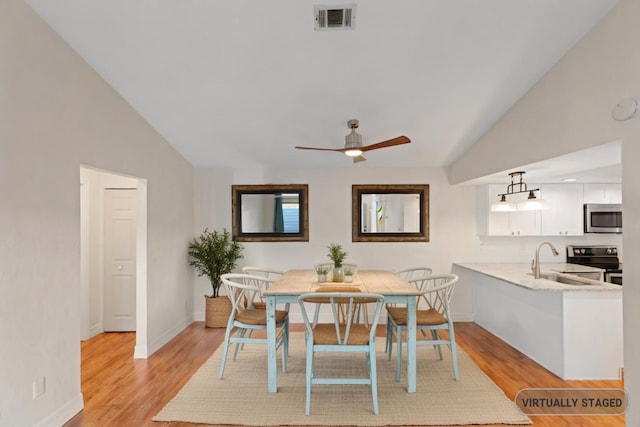 dining room featuring sink, vaulted ceiling, light wood-type flooring, and ceiling fan