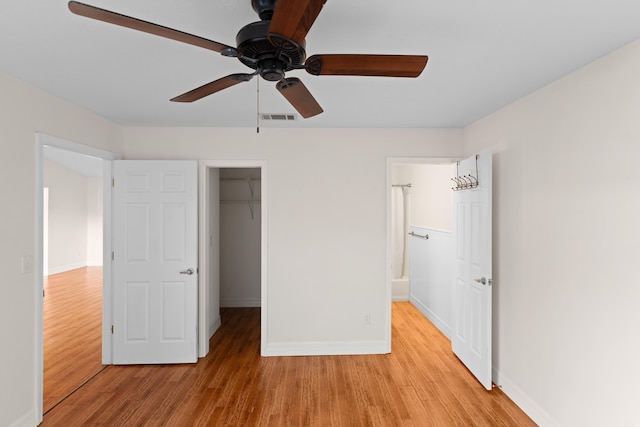 unfurnished bedroom with light hardwood / wood-style floors, ceiling fan, a spacious closet, and a closet