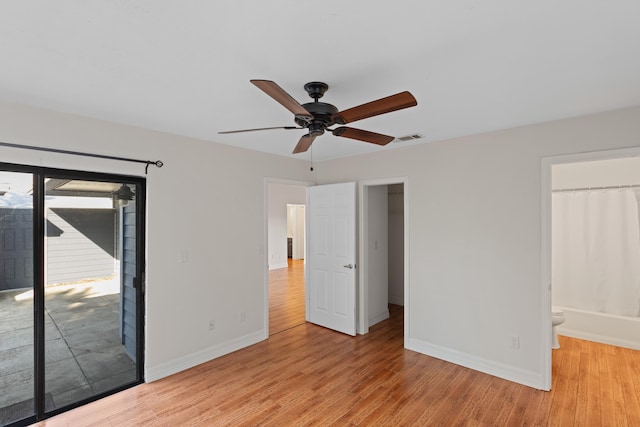 unfurnished bedroom featuring access to outside, ensuite bath, ceiling fan, and light hardwood / wood-style floors