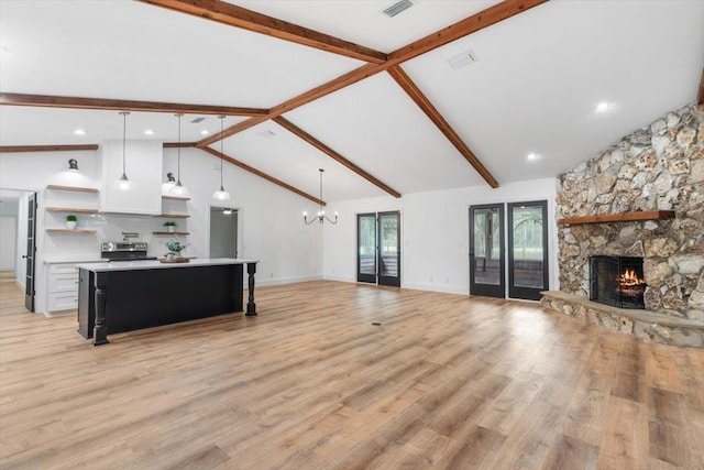 living area featuring beamed ceiling, an inviting chandelier, a fireplace, and light wood-style floors