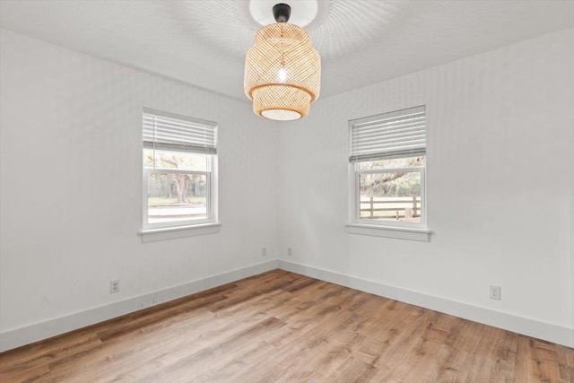 empty room with baseboards, plenty of natural light, and wood finished floors