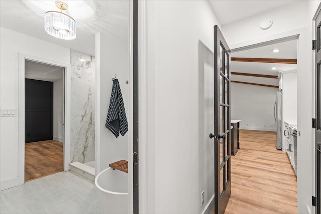 hall featuring beam ceiling and light wood-style floors