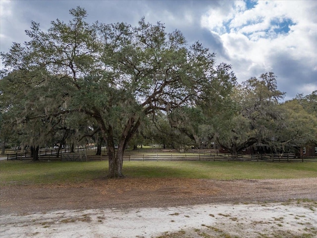 exterior space featuring a rural view, a yard, and fence