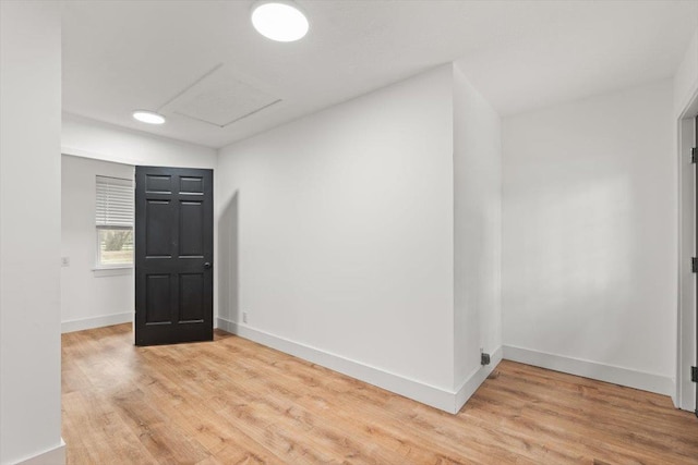 spare room featuring baseboards, attic access, and light wood-style flooring