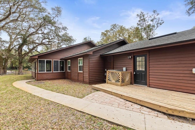 exterior space featuring a front lawn and a wooden deck