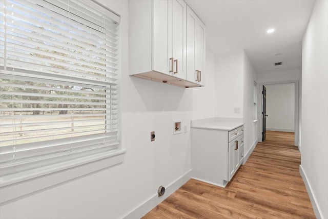 washroom with hookup for a washing machine, baseboards, hookup for an electric dryer, light wood-style flooring, and cabinet space