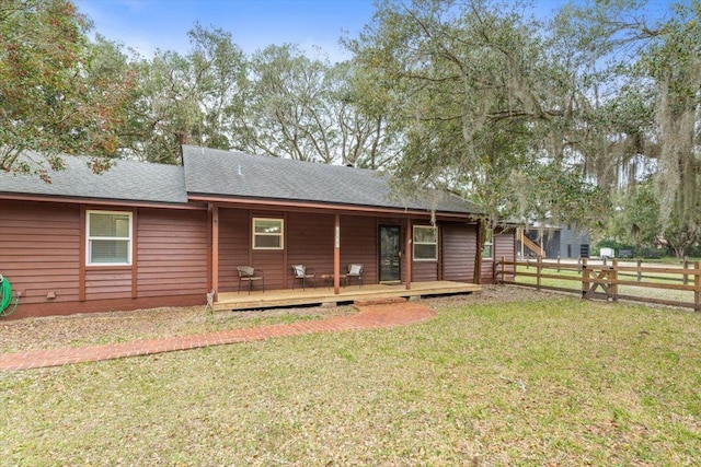 rear view of house featuring a wooden deck, a lawn, and fence