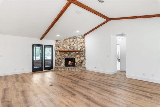 unfurnished living room featuring a fireplace, light wood-type flooring, lofted ceiling with beams, and baseboards