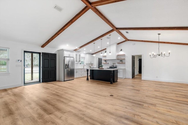 unfurnished living room with visible vents, beamed ceiling, light wood-style flooring, an inviting chandelier, and baseboards