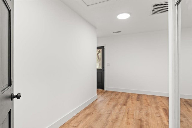 hallway featuring visible vents, light wood-style flooring, and baseboards