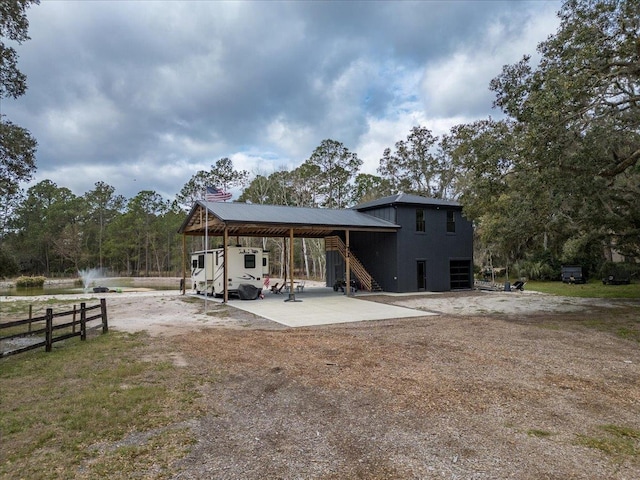 back of house with a carport, stairway, and metal roof