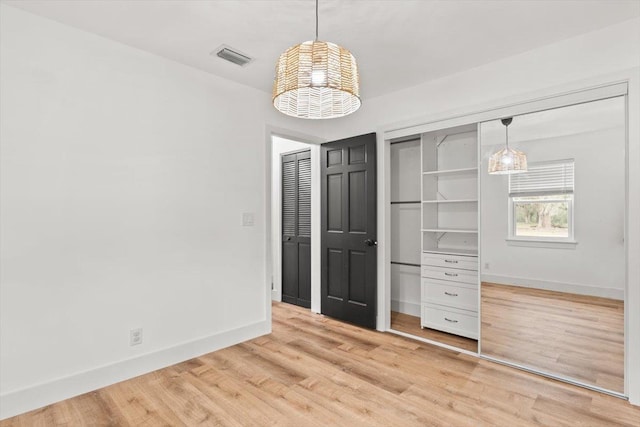 unfurnished bedroom with light wood-style flooring, visible vents, and baseboards