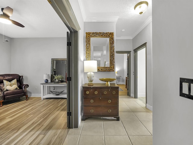 corridor featuring baseboards, a textured ceiling, light wood-style floors, and crown molding
