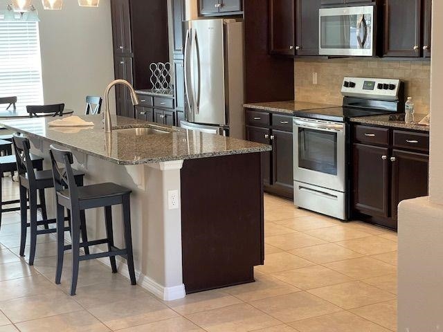 kitchen featuring a sink, backsplash, light tile patterned floors, and stainless steel appliances