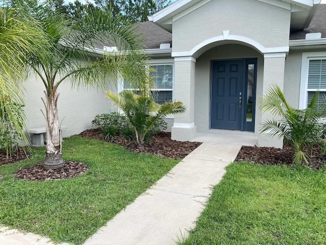 52 Fanshawe Ln, Palm Coast, FL 32137 - doorway to property featuring stucco siding and a lawn