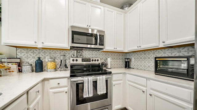 kitchen with white cabinets, backsplash, and appliances with stainless steel finishes