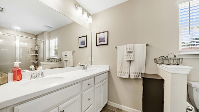 bathroom featuring vanity, a healthy amount of sunlight, an enclosed shower, and toilet