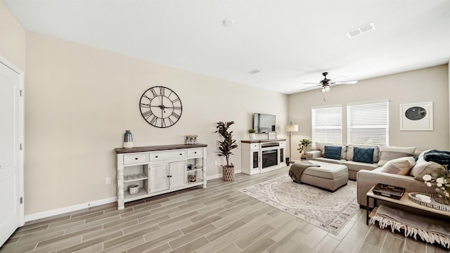 living room with ceiling fan, a fireplace, and light wood-type flooring