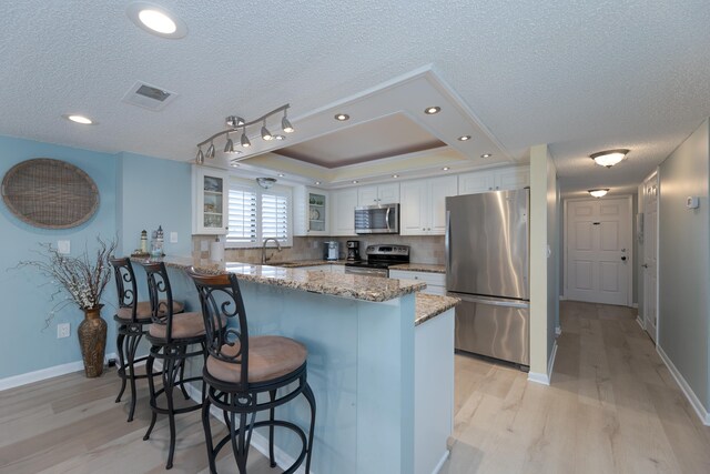 850 A1A Beach Blvd Unit 74, Saint Augustine Beach, FL 32080 - kitchen with stainless steel appliances, light wood-style flooring, a peninsula, glass insert cabinets, and white cabinetry