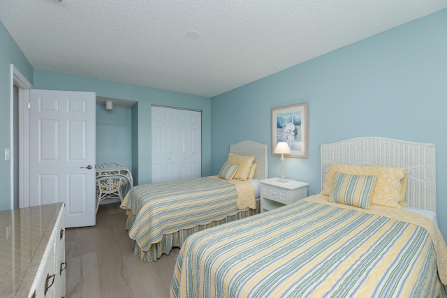 bedroom featuring a closet, light hardwood / wood-style floors, and a textured ceiling