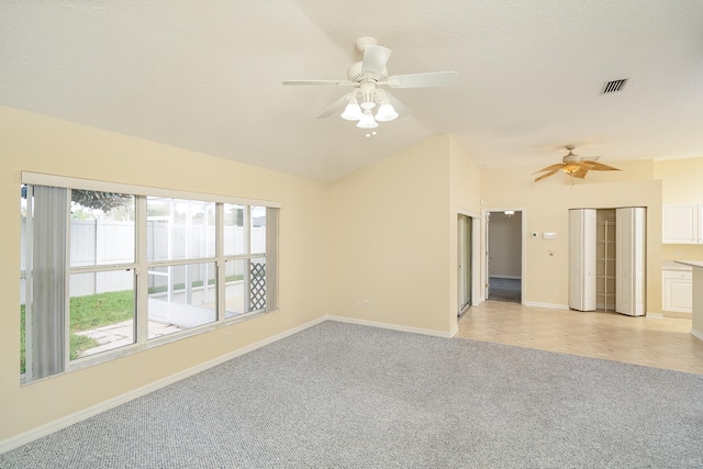 carpeted spare room featuring a textured ceiling, ceiling fan, and vaulted ceiling