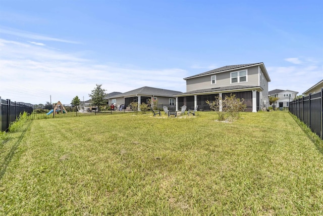 back of property featuring a playground and a lawn