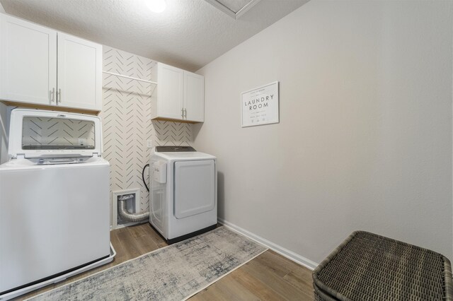 washroom featuring cabinets, dark hardwood / wood-style flooring, washing machine and clothes dryer, and a textured ceiling