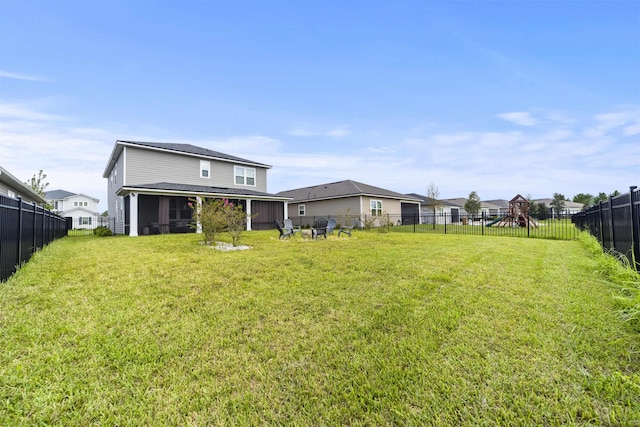 rear view of property with a playground and a yard