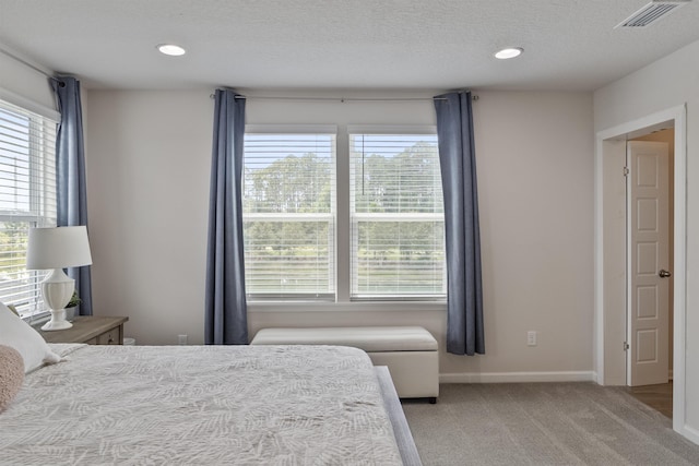 bedroom with light colored carpet and a textured ceiling