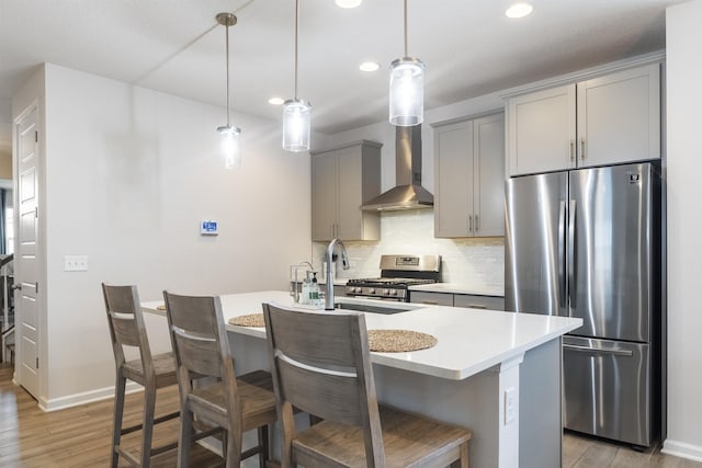 kitchen with decorative light fixtures, light hardwood / wood-style flooring, gray cabinets, an island with sink, and stainless steel appliances