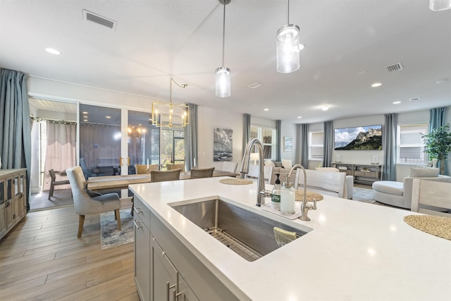 kitchen featuring a chandelier, sink, pendant lighting, and light hardwood / wood-style floors