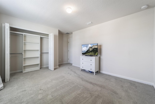 unfurnished bedroom featuring a closet, light carpet, and a textured ceiling