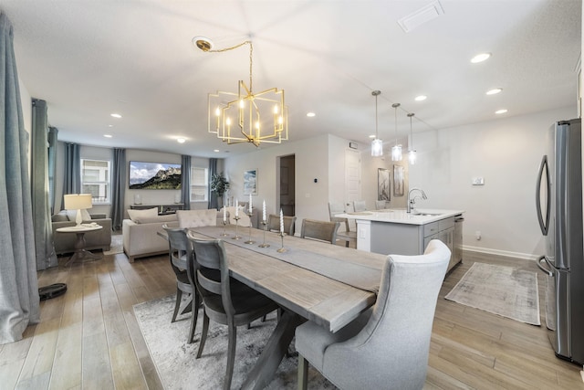 dining space featuring sink, an inviting chandelier, and light wood-type flooring