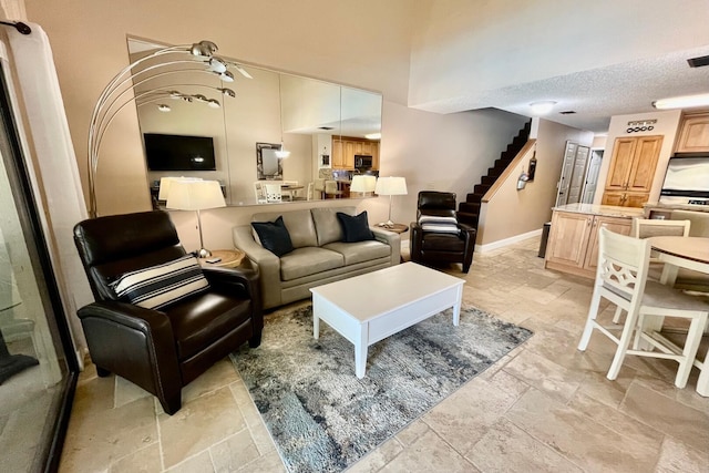 living room featuring visible vents, baseboards, stairs, a textured ceiling, and stone tile flooring