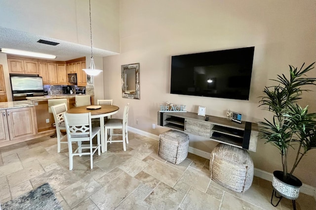 interior space featuring baseboards, a textured ceiling, visible vents, and stone tile floors