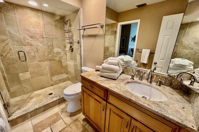 full bathroom featuring toilet, visible vents, vanity, a shower stall, and stone tile flooring