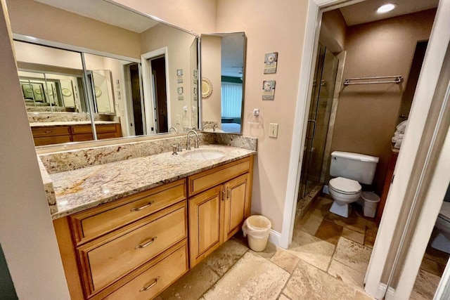 full bath with toilet, stone tile floors, vanity, baseboards, and a shower stall